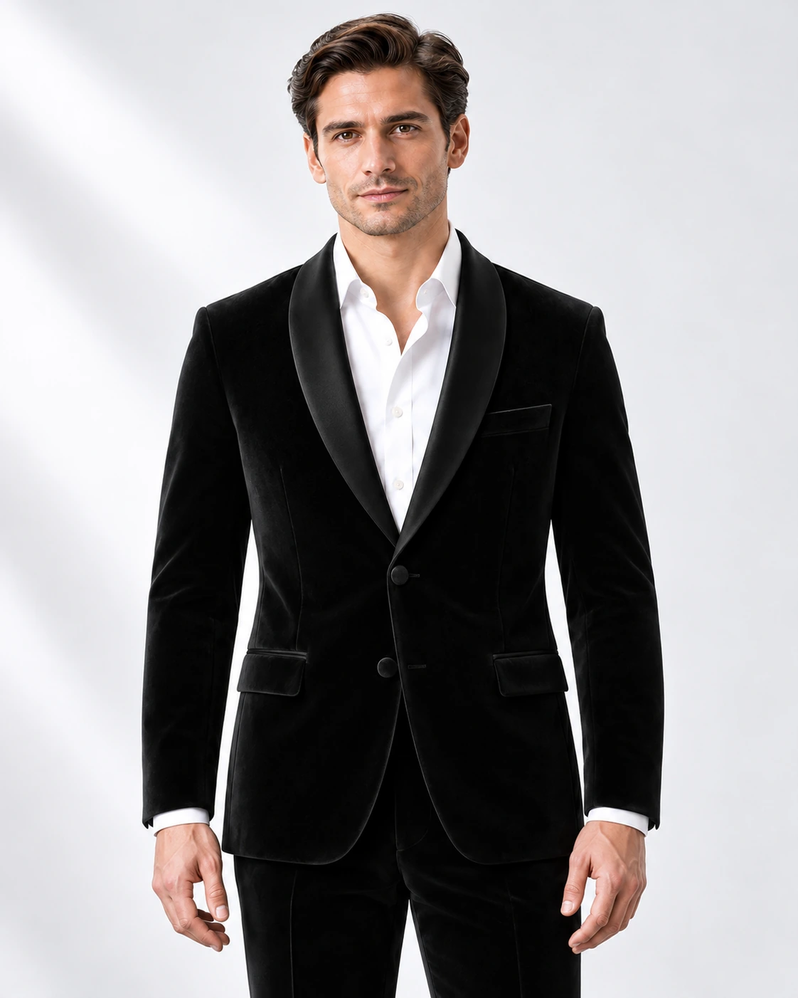 Man wearing a black velvet single-breasted tuxedo with black satin shawl collar, head-to-upper-thigh portrait against a white studio background.