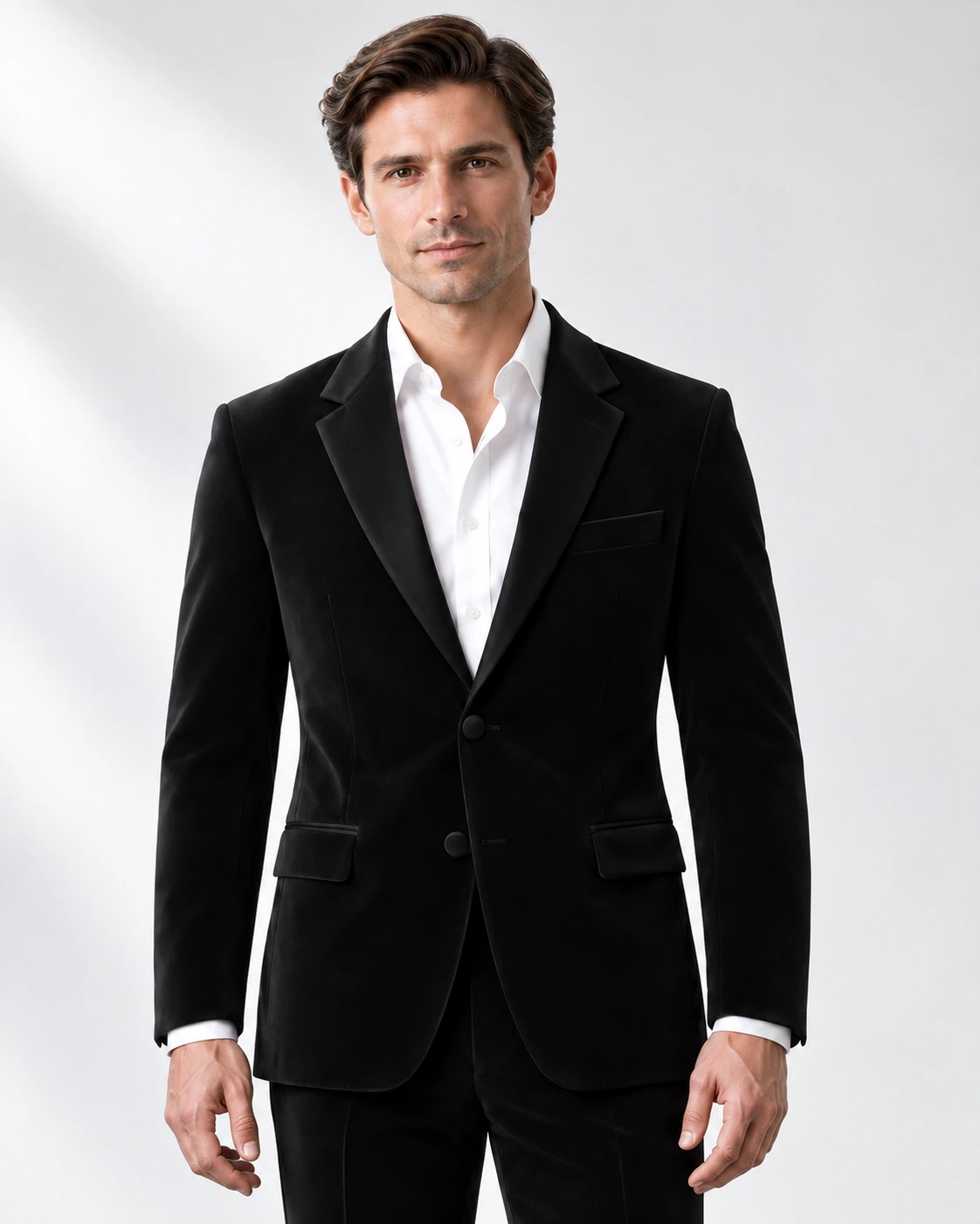 Man wearing a classic black wool single-breasted tuxedo with black satin notch lapels and collar, head-to-upper-thigh portrait against a white studio background.