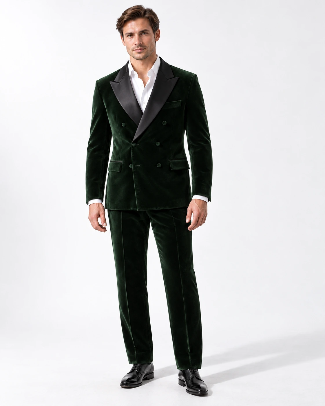 Man wearing a green velvet double-breasted tuxedo with black satin peak lapels and collar, full-length against a white studio background.