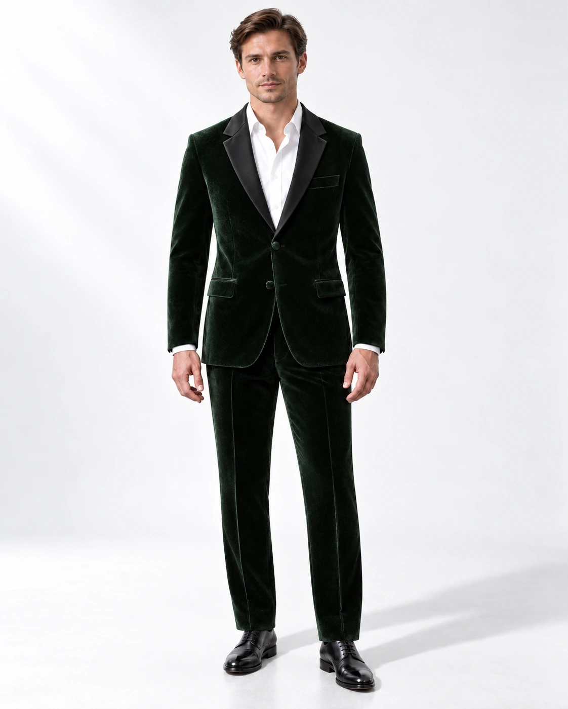 Man wearing a green velvet single-breasted tuxedo with black satin notch lapels and collar, full-length against a white studio background.