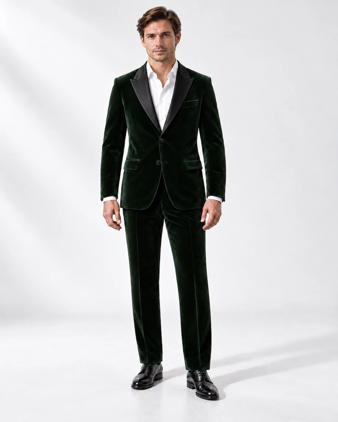 Man wearing a green velvet single-breasted tuxedo with black satin peak lapels and collar, full-length against a white studio background.