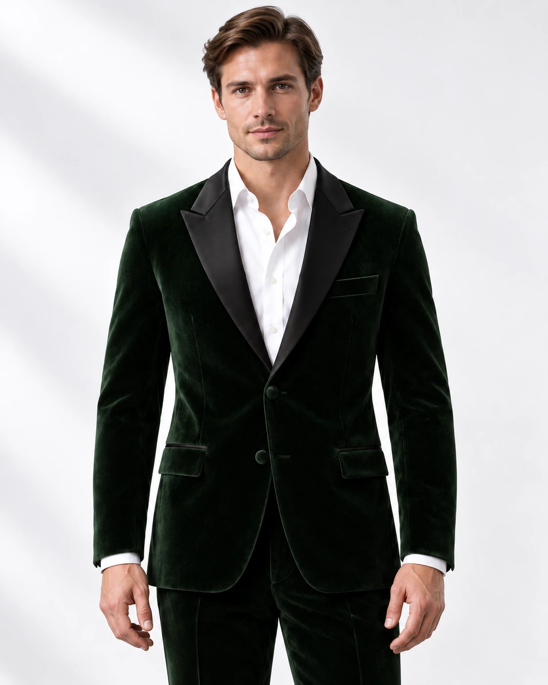 Man wearing a green velvet single-breasted tuxedo with black satin peak lapels and collar, head-to-upper-thigh portrait against a white studio background.