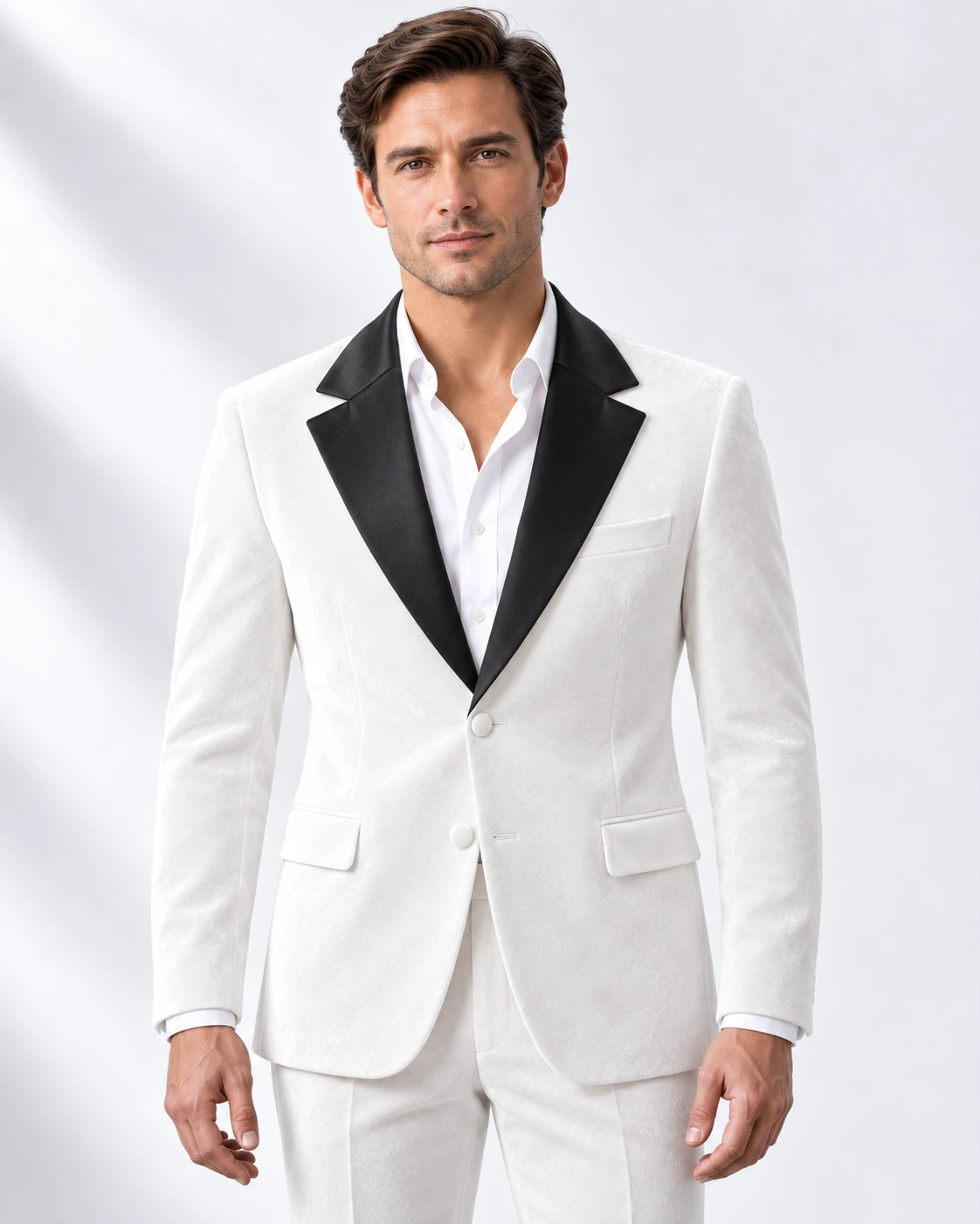 Man wearing a white velvet single-breasted tuxedo with black satin notch lapels and collar, head-to-upper-thigh portrait against a white studio background.