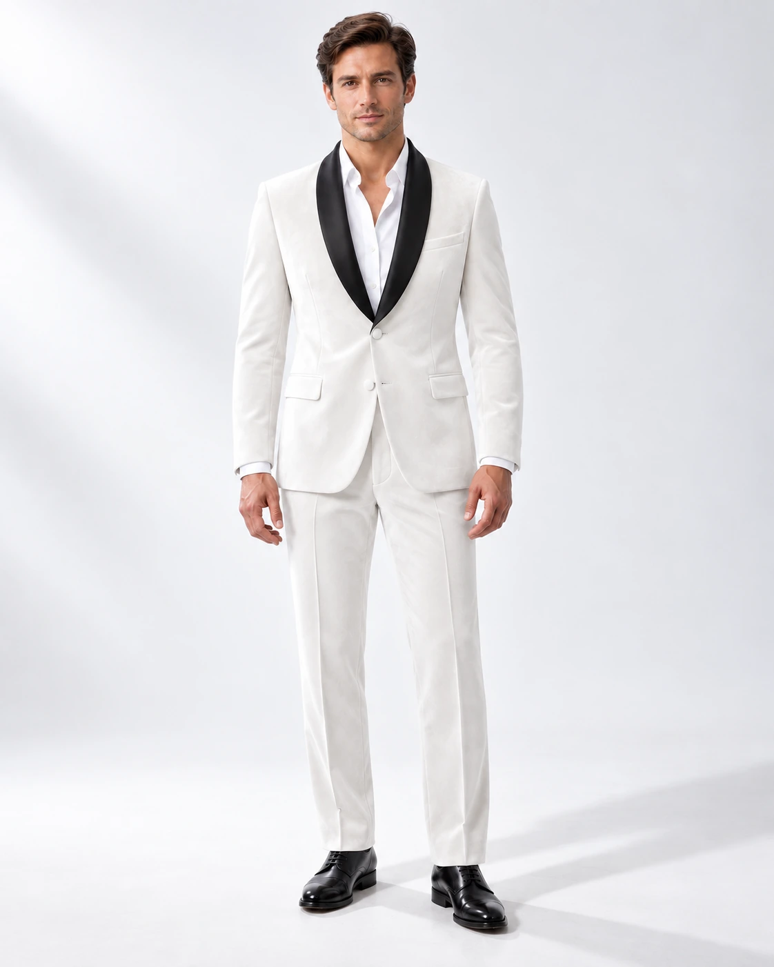 Man wearing a white velvet single-breasted tuxedo with black satin shawl collar, full-length against a white studio background.