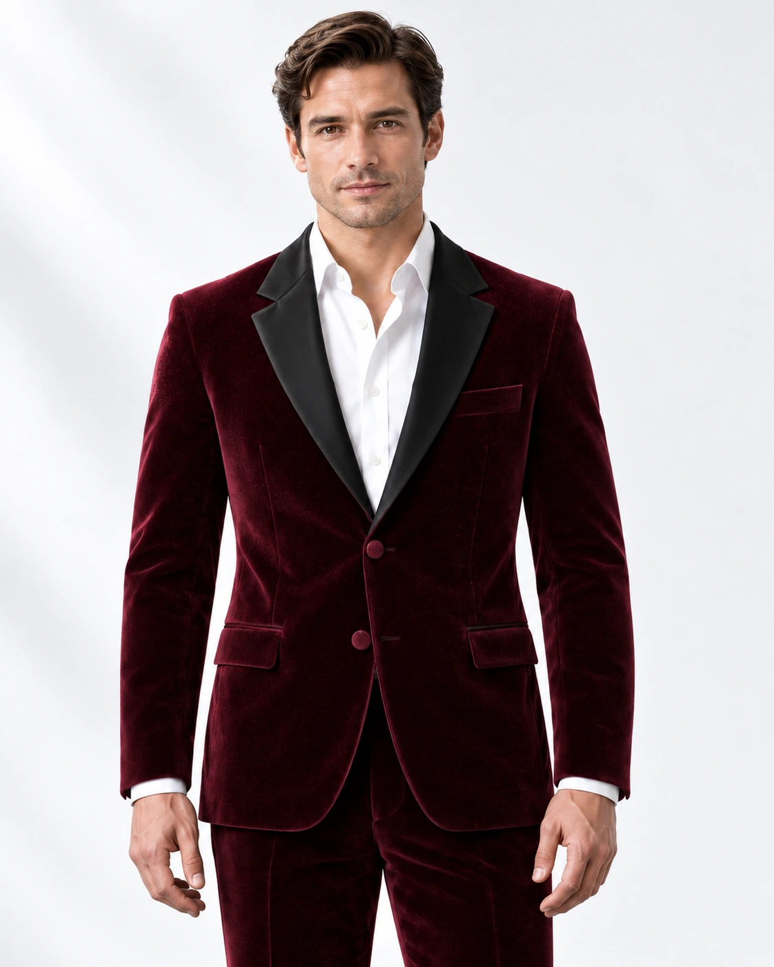 Man wearing a wine velvet single-breasted tuxedo with black satin notch lapels and collar, head-to-upper-thigh portrait against a white studio background.