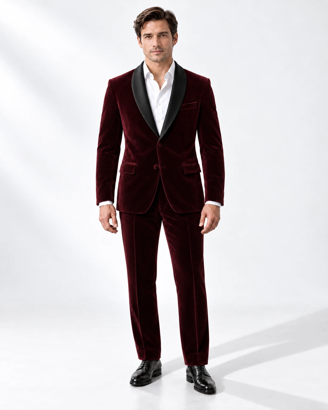 Man wearing a wine velvet single-breasted tuxedo with black satin shawl collar, full-length against a white studio background.